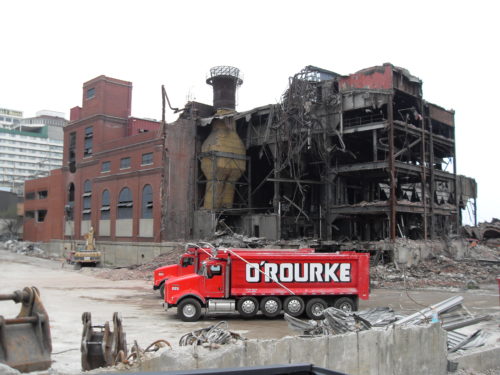 O'Rourke dumpster trucks in front of broken building brownfield site