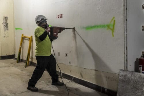 Worker tearing down a wall in a commercial building for renovation