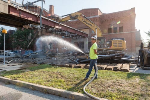 woman watering debris to minimize dust