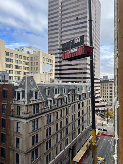 O'Rourke dumpster raised on a crane in downtown for demolition