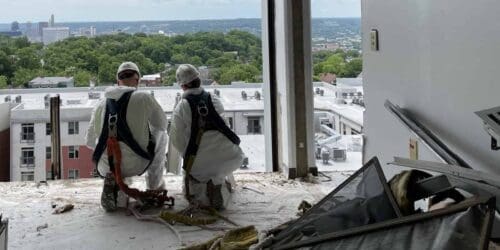 two workers looking over the edge of a building during abatement