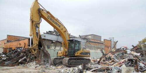 excavator doing demo work outside of a building